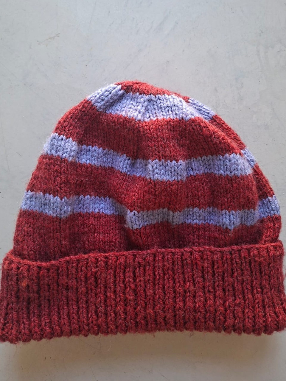 Red beanie with periwinkle blue stripes, hand-knitted at Kranshoek