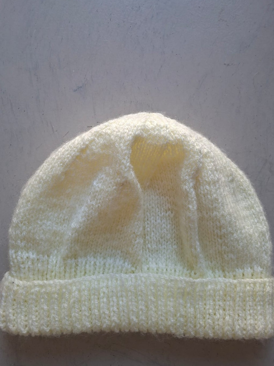 Plain pale cream beanie with a folded cuff, hand-knitted at Kranshoek