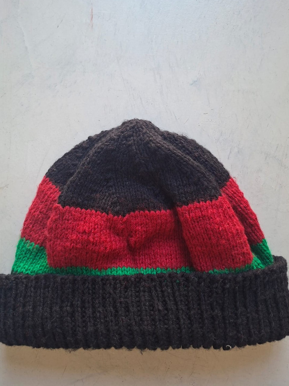 Charcoal beanie with red and green bands, hand-knitted at Kranshoek