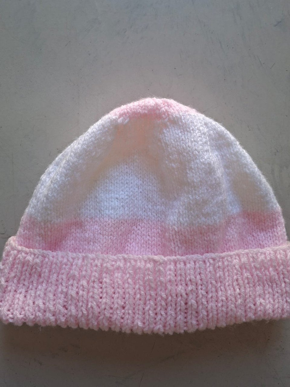 Pink beanie fading to white with a pink cuff, hand-knitted at Kranshoek