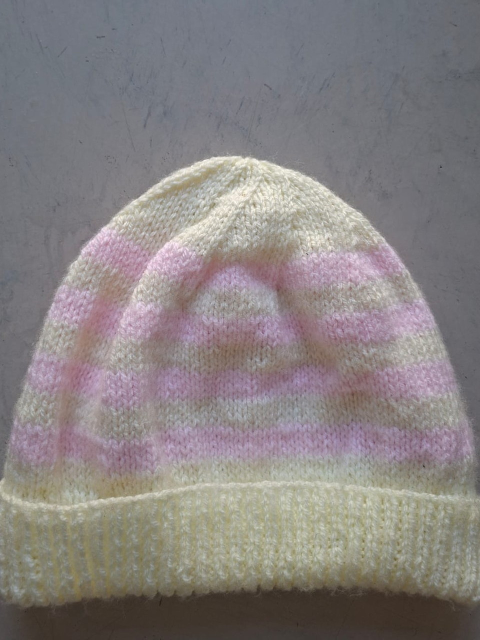 Cream beanie with a soft pink blush through the crown, hand-knitted at Kranshoek