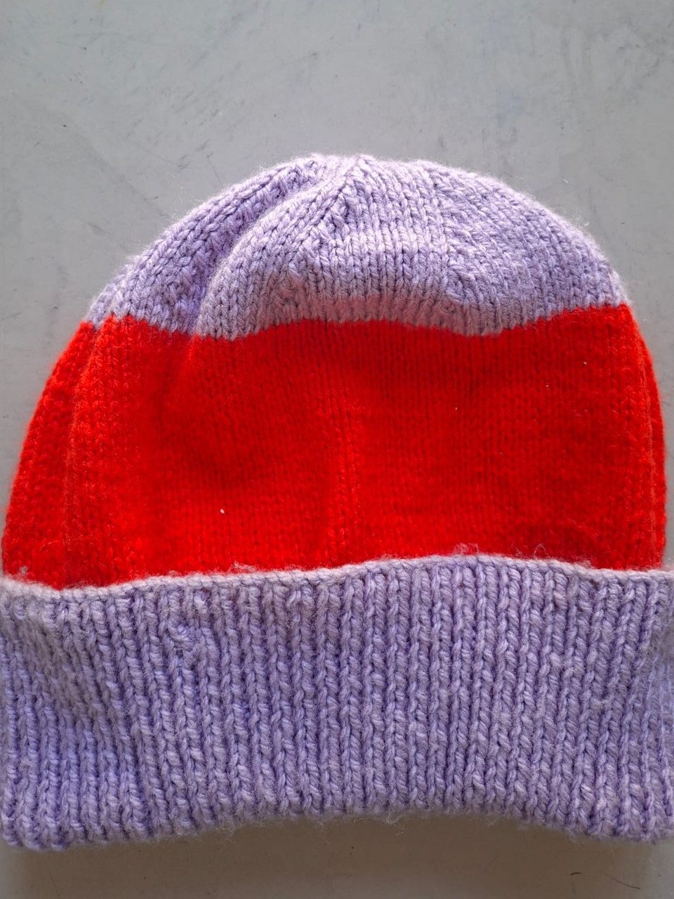 Lilac beanie with a wide red band, hand-knitted at Kranshoek