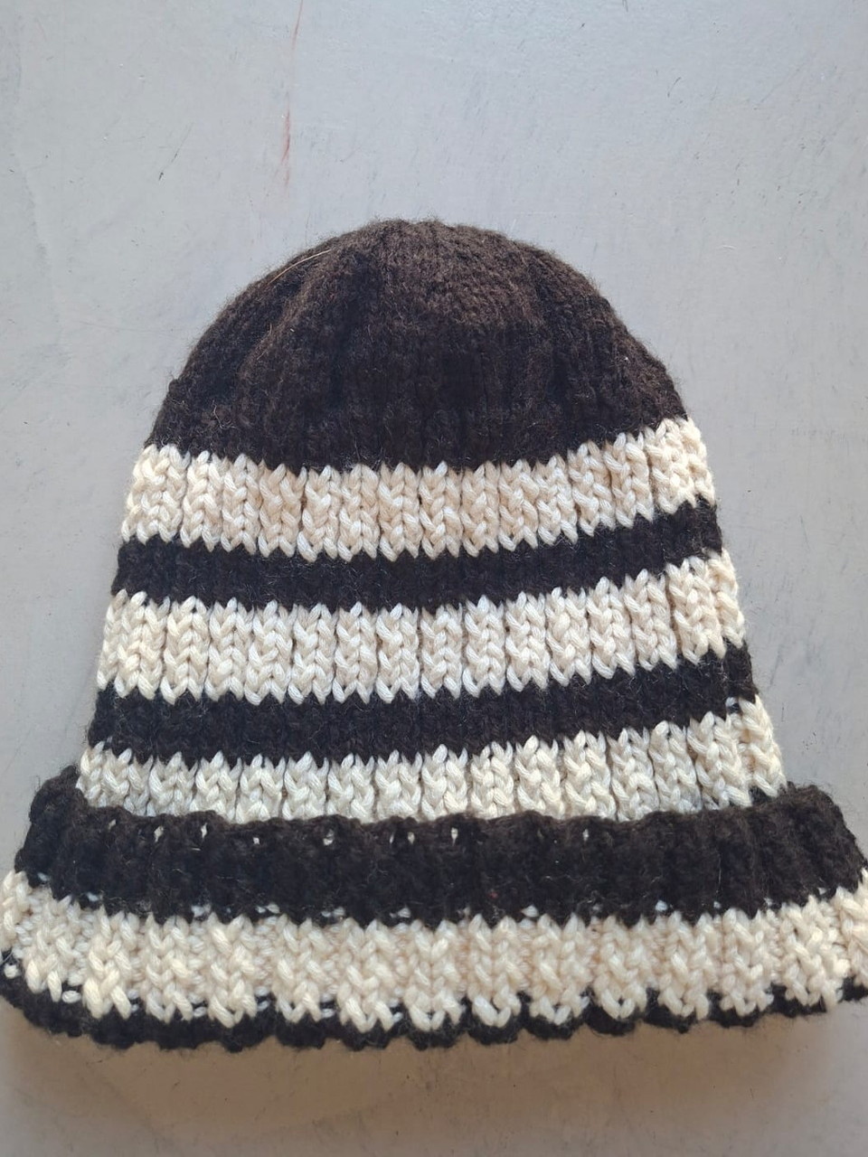 Dark brown beanie with cream textured stripes and a scalloped edge, hand-knitted at Kranshoek