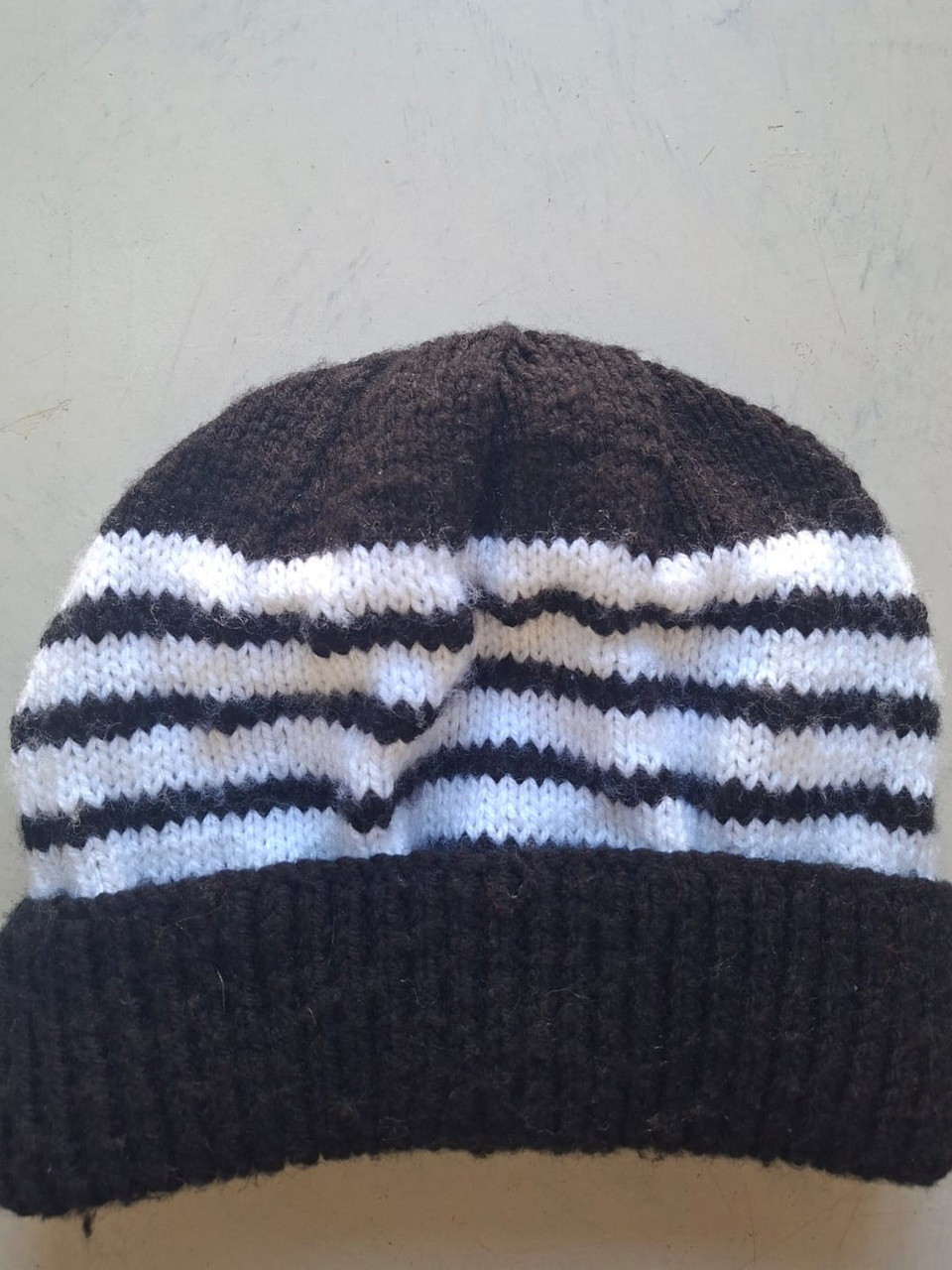 Dark brown beanie with white stripes, hand-knitted at Kranshoek