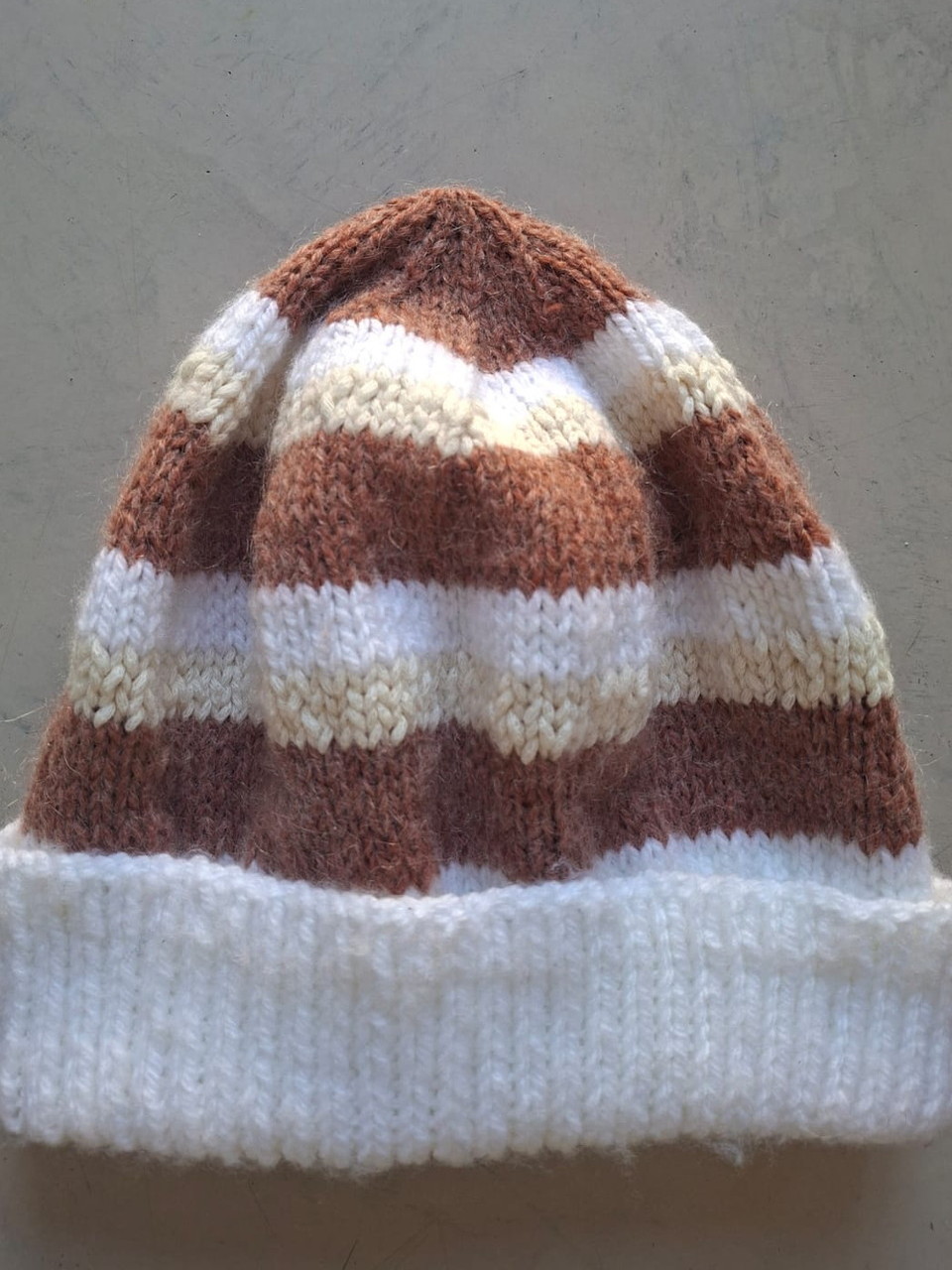 Brown, tan and cream striped beanie with a white cuff, hand-knitted at Kranshoek