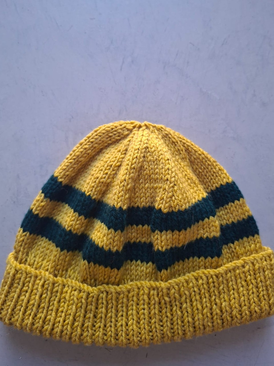 Mustard gold beanie with dark teal stripes, hand-knitted at Kranshoek